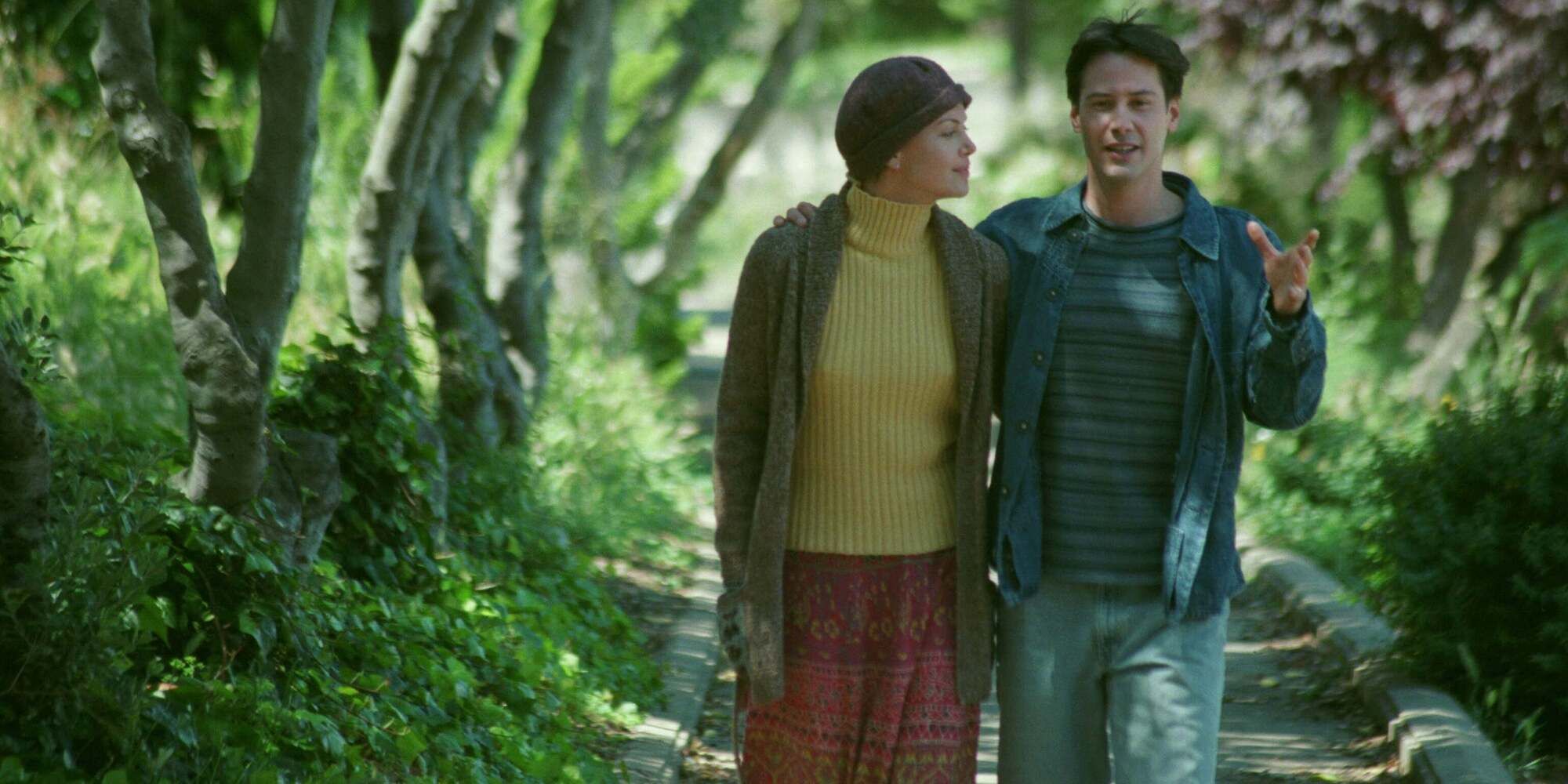 Keanu Reeves as Nelson Moss and Charlize Theron as Sara Deever walking down a forest path together in 'Sweet November' (2001)