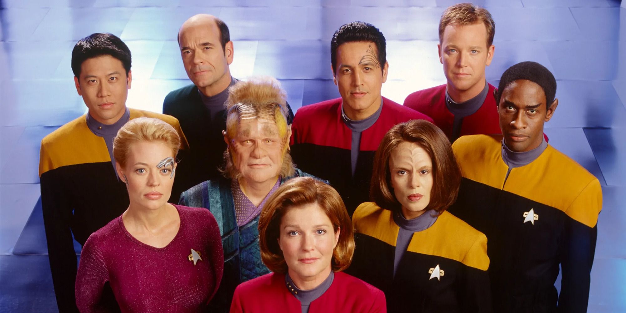 The cast of 'Star Trek Voyager' in their Starfleet uniforms looking up at the camera.