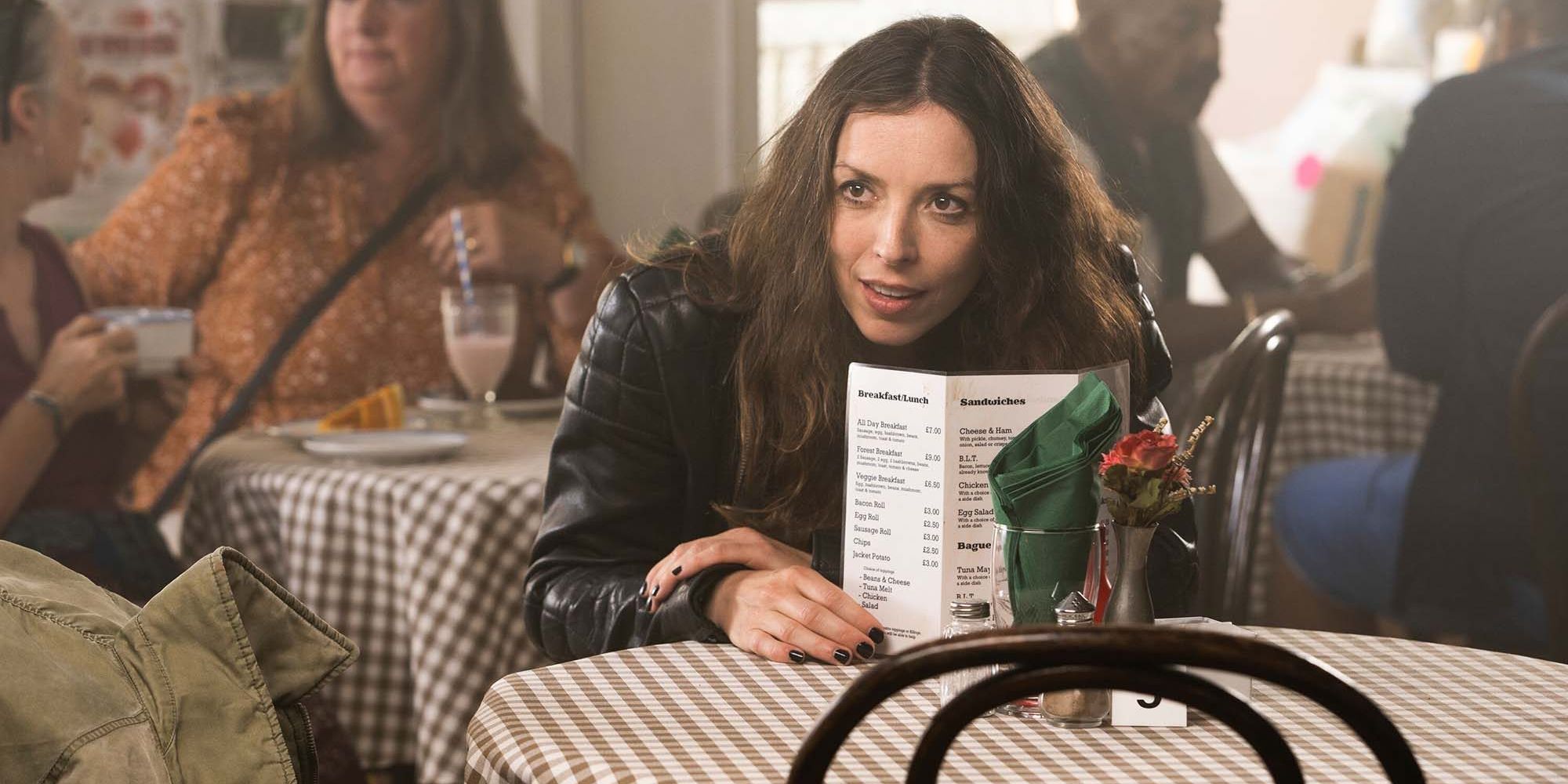 Bridget Christie talking from behind a menu in a cafe in 'The Change' Season 1