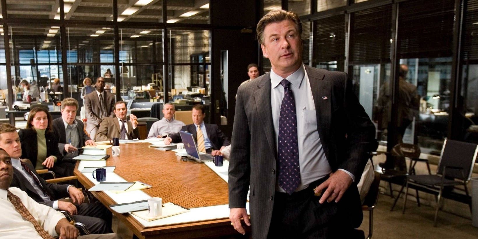 Alec Baldwin as Captain Ellerby stands at the head of a table in The Departed.