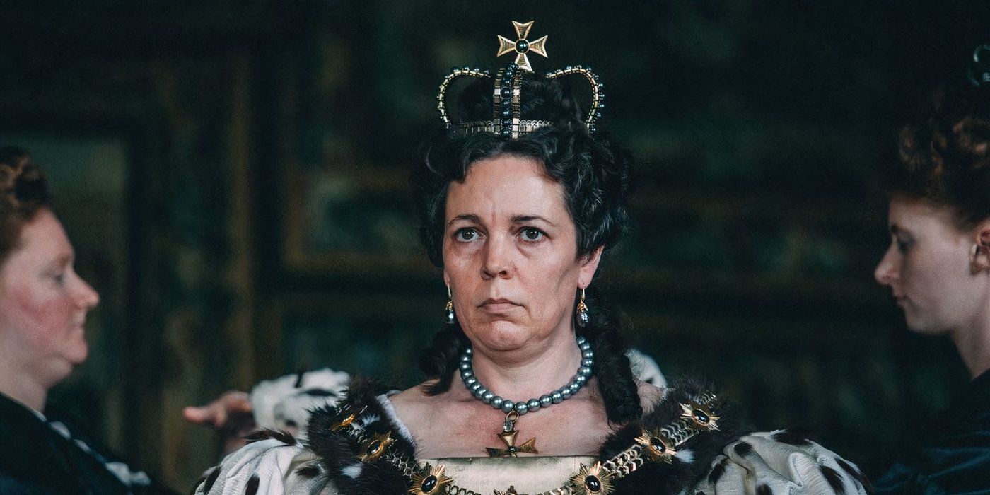 Olivia Colman wears a royal crown and grand dress and looks serious in The Favourite.