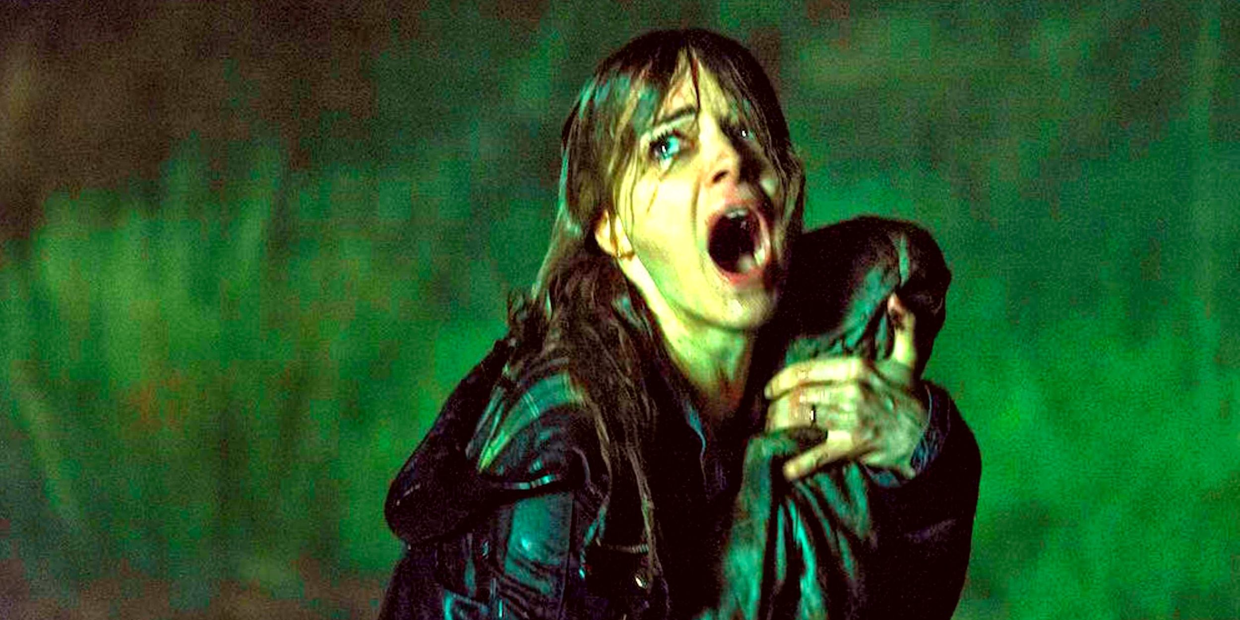 Claire Hitchens, played by actor Bojana Novakovic, outside in the dark while clutching a bundle in her arms and screaming in The Hallow.