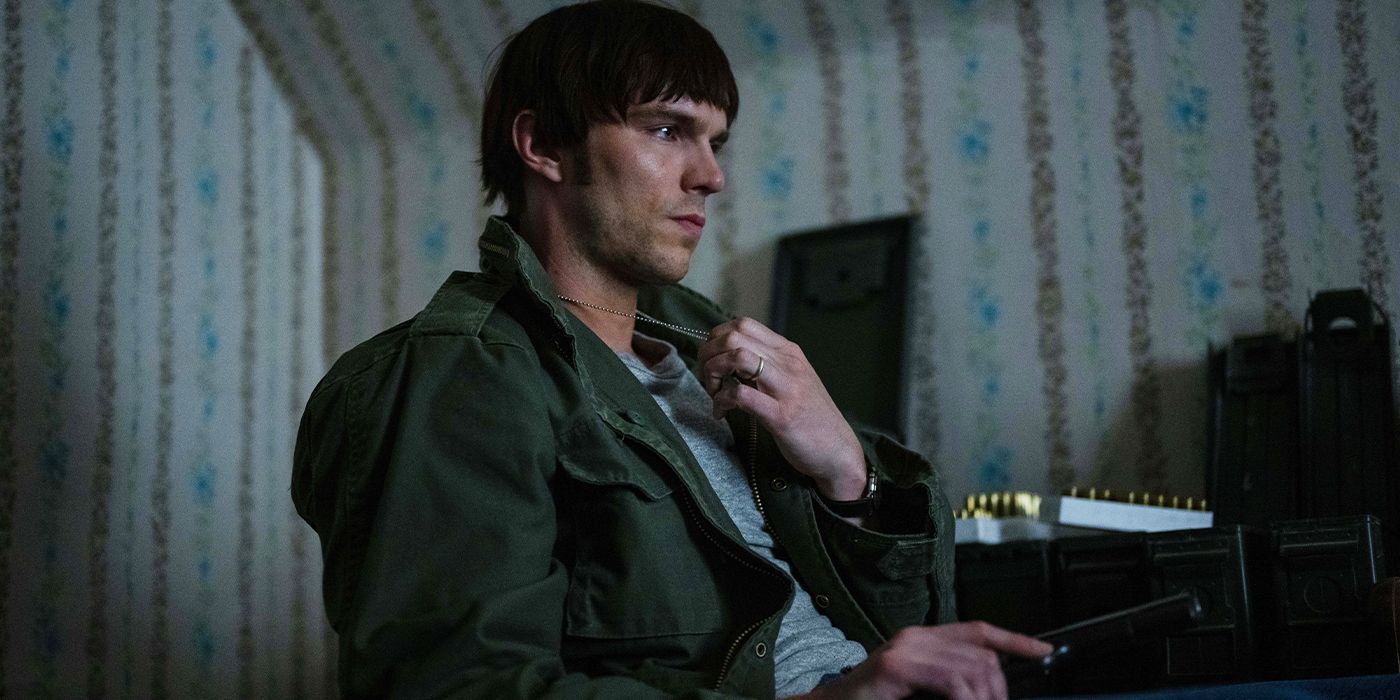 Mathews (Nicholas Hoult) sitting in a chair holding a gun in his lap