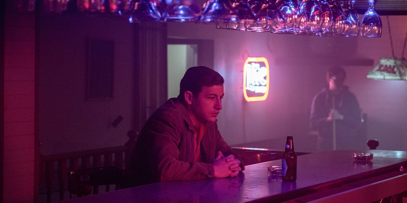 Bowen (Tye Sheridan) leaning on a bar in purple lighting with his hands folded looking pensive