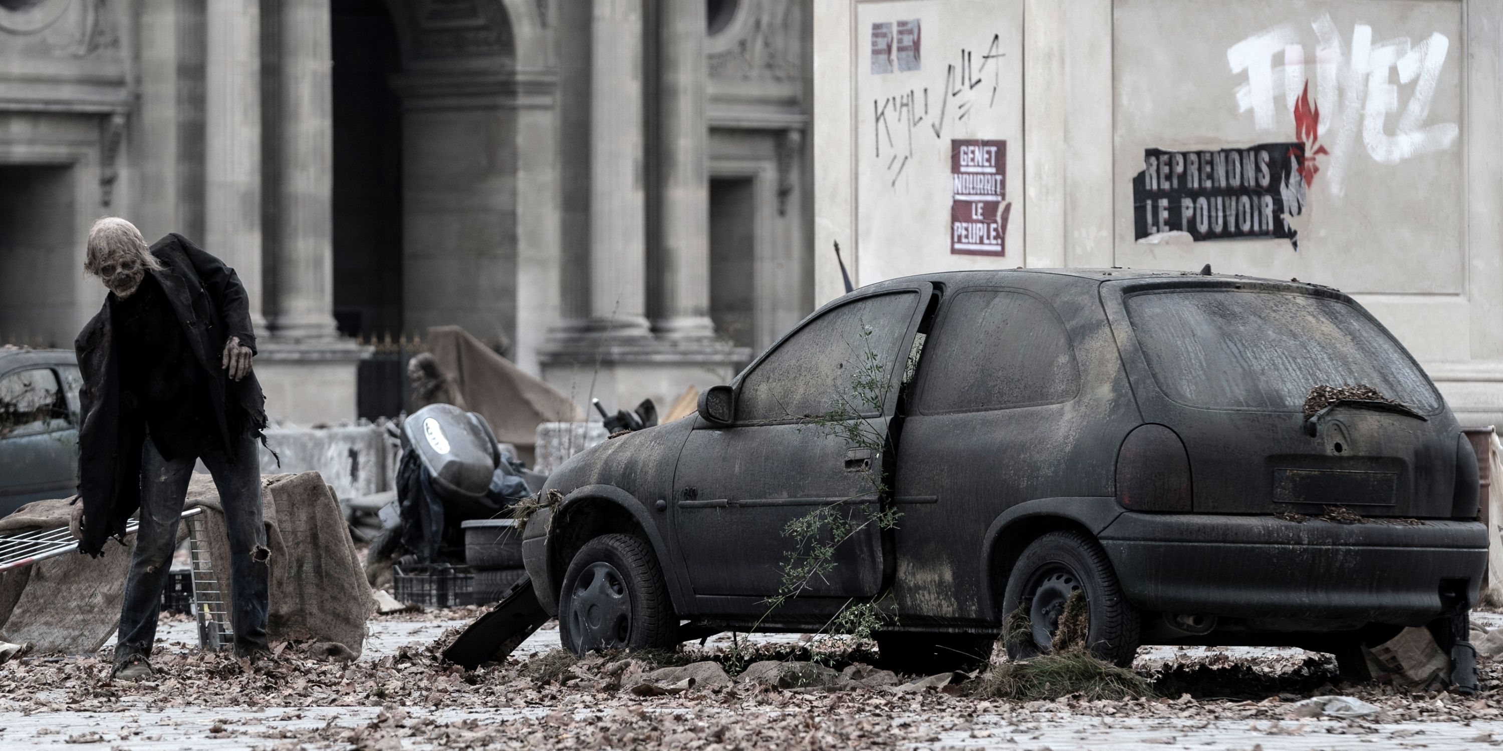 A Walker stumbling past an abandoned car with his left shoulder up in The Walking Dead: Daryl Dixon Season 2