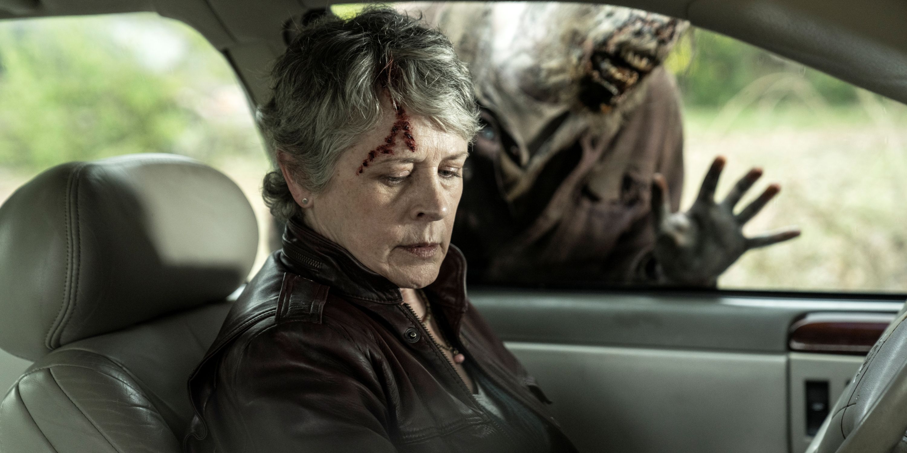 Melissa McBride as Carol in a car with a zombie banging on her window in The Walking Dead: Daryl Dixon