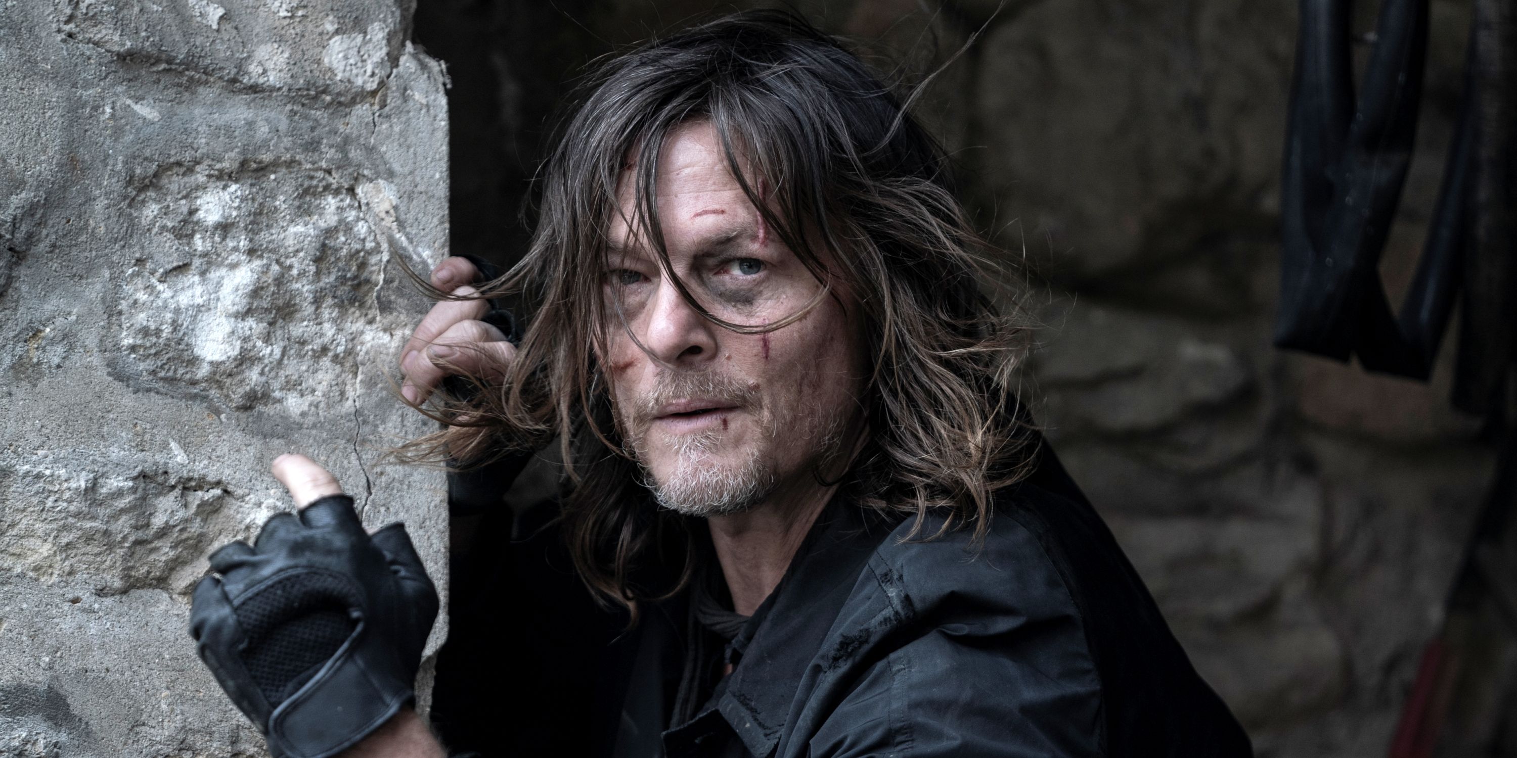 Norman Reedus as Daryl Dixon holding onto the side of a wall in The Walking Dead: Daryl Dixon Season 2