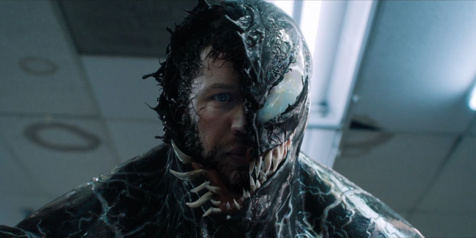 The face of Eddie Brock, played by Tom Hardy, peaks out from beneath Venom in 'Venom'.