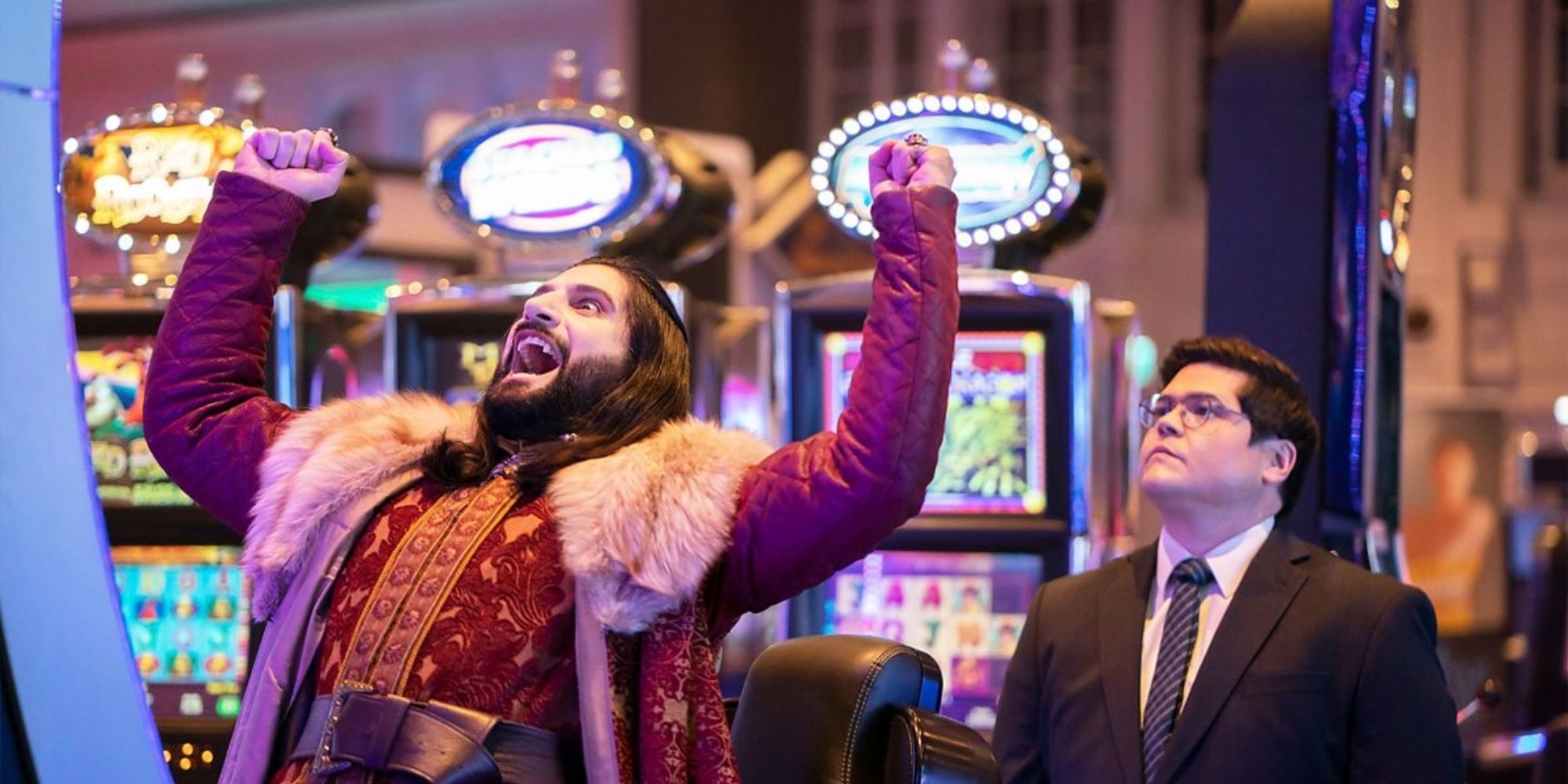 Nandor shouts in triumph at a casino as Guillermo looks on unamused in What We Do in the Shadows.