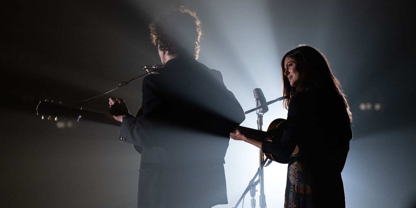 Timothee Chalamet and Monica Barbaro performing on stage as Bob Dylan and Joan Baez in A Complete Unknown.