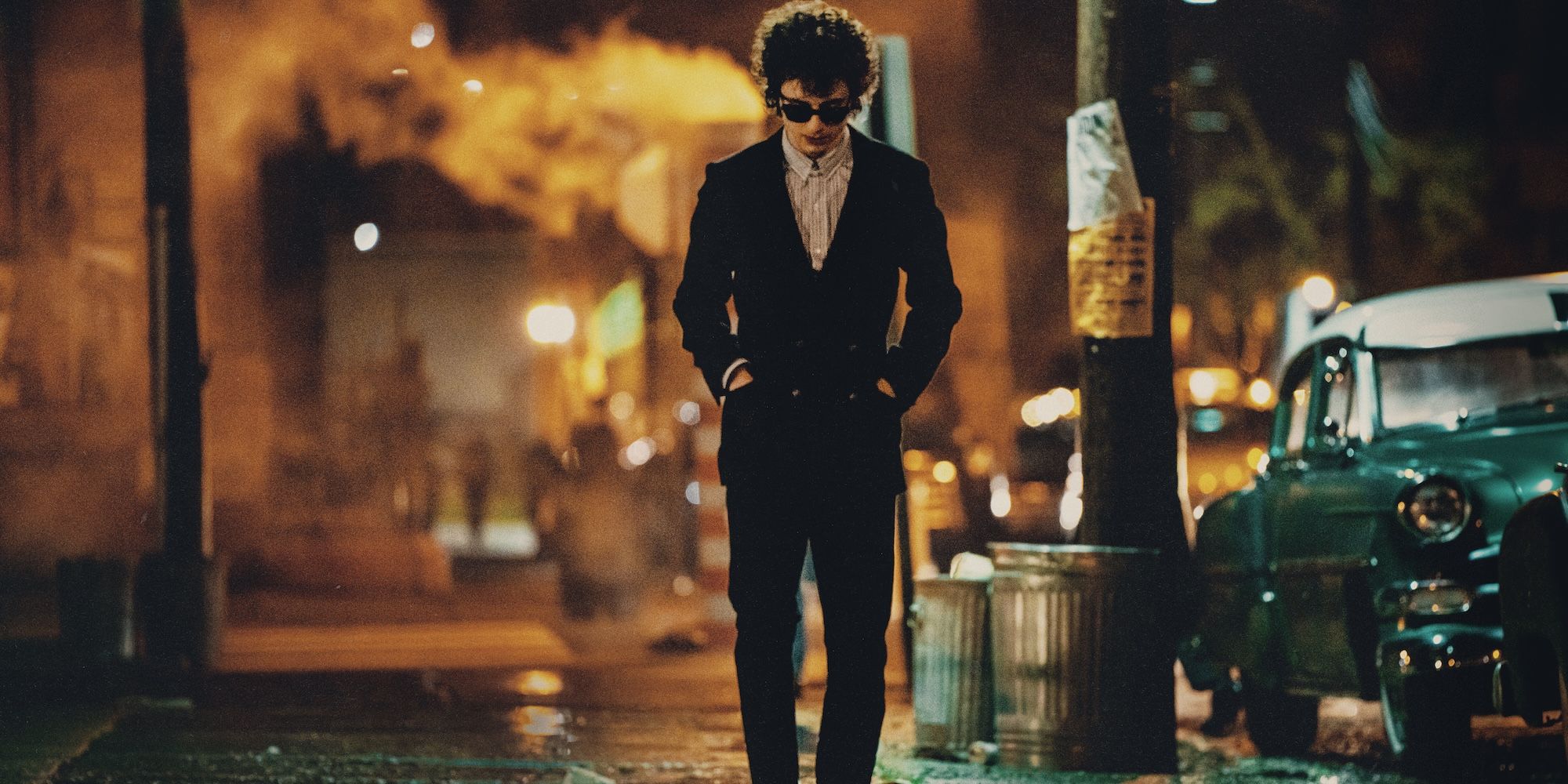 Timothée Chalamet, walking down a street, as Bob Dylan in A Complete Unknown