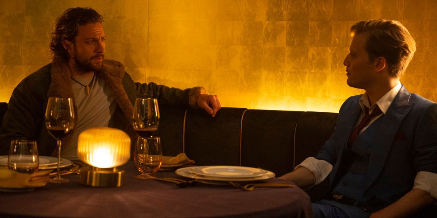 Aaron Taylor-Johnson and Fred Hechinger sitting at a restaurant table as Sergei and Dmitri in Kraven the Hunter.