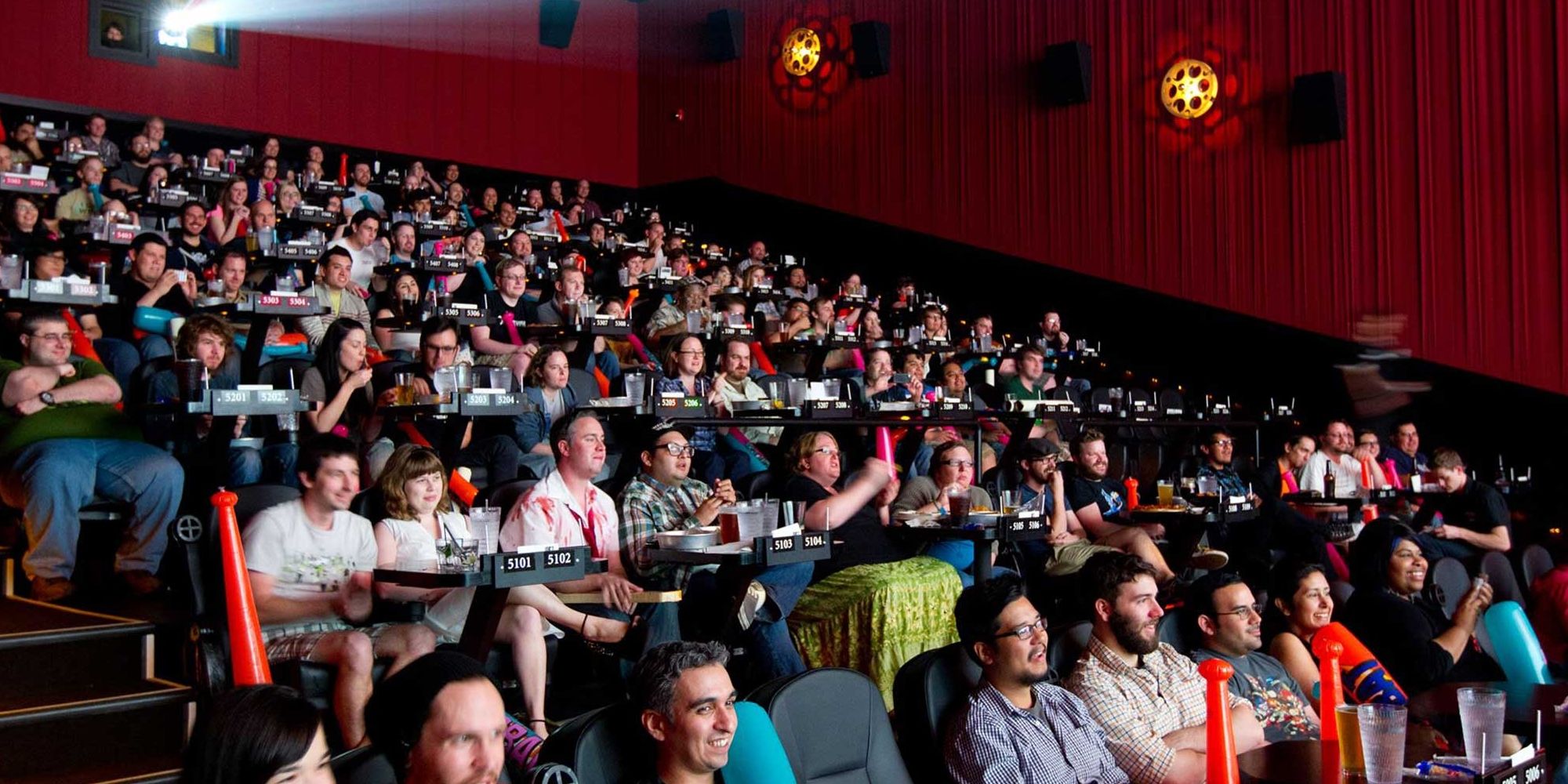 An audience of moviegoers seated inside an Alamo Drafthouse movie theater