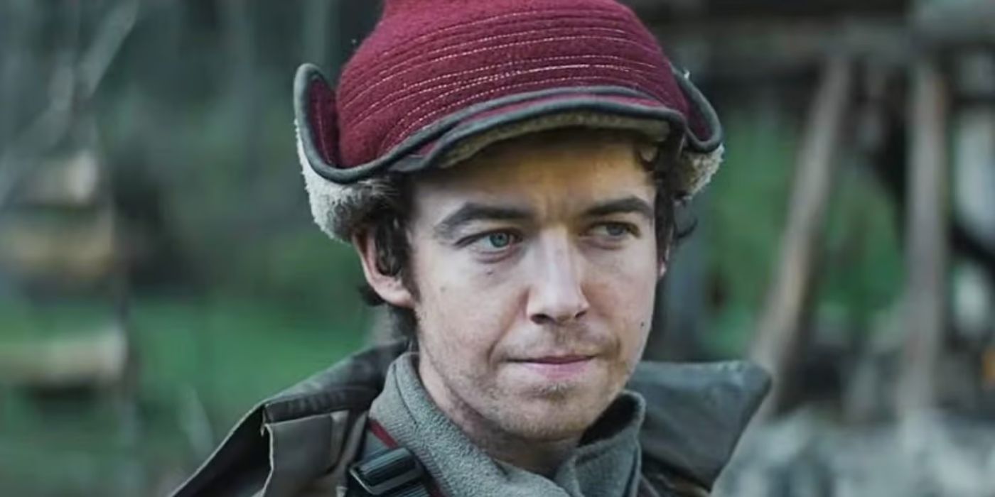 Alex Lawther as Karis Nemik wearing a hat and coat and standing outside looking off camera in Andor.