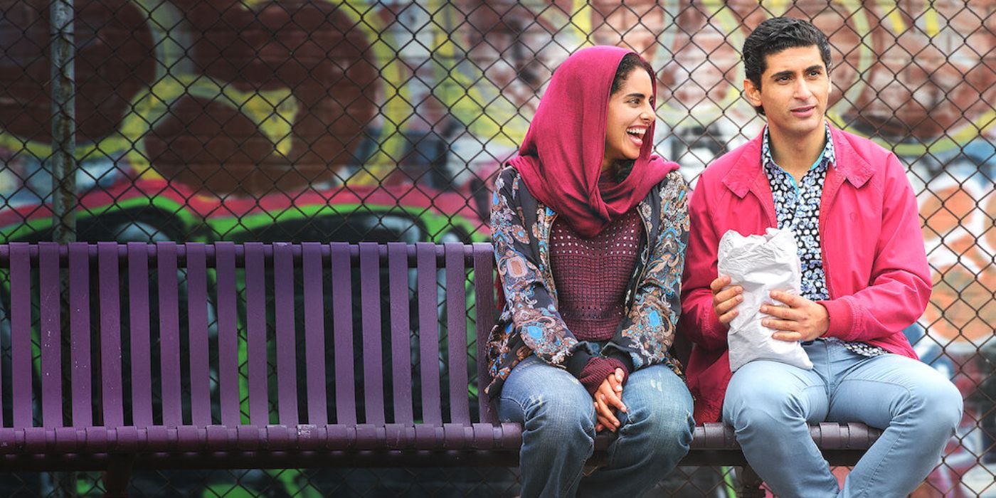 Ali (Osamah Sami) and Dianne (Helana Sawires) sitting next to each other on a bench, laughing.