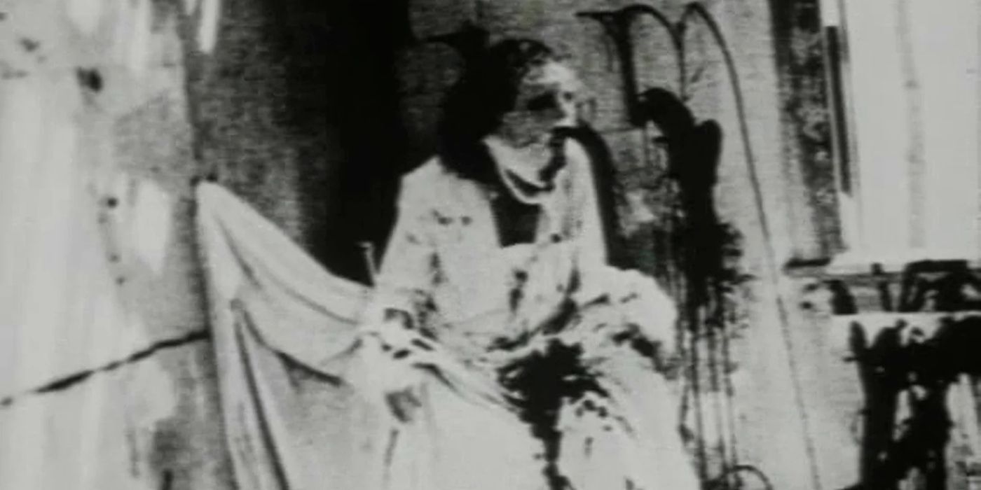 God, portrayed by Brian Salzberg, wears a haunting mask with a long, open mouth and trembles in the corner of a room.