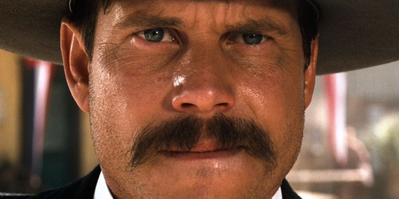 A super closeup of Bill Paxton as Morgan Earp sweating, wearing a black cowboy hat in Tombstone.