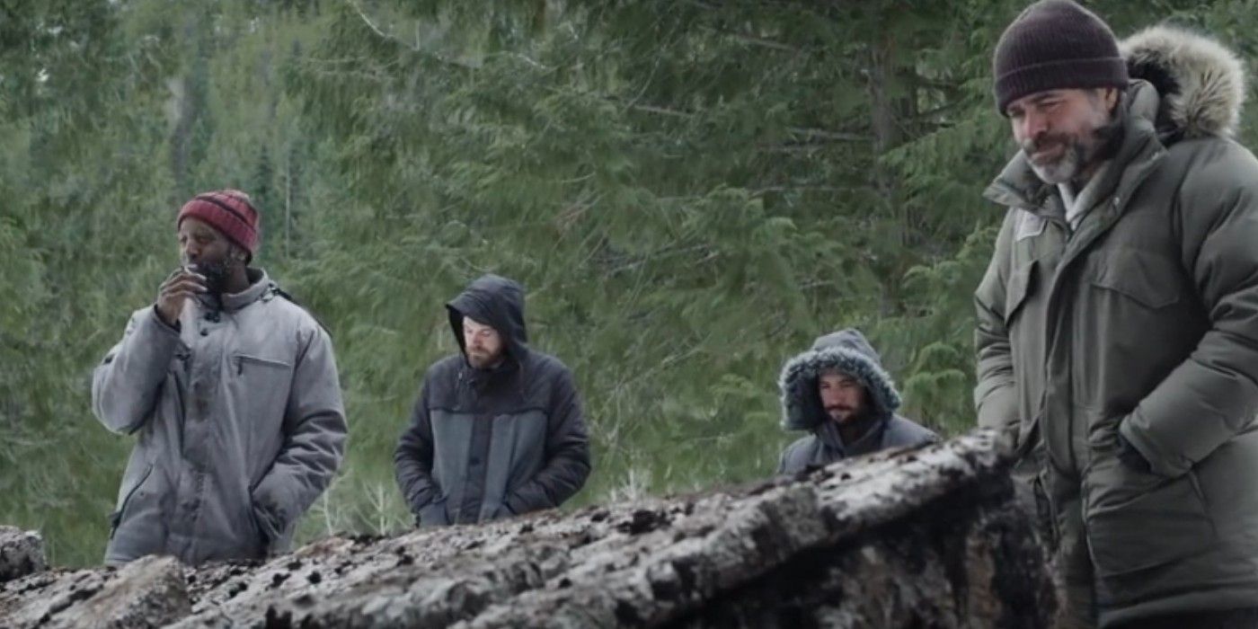 Marc Anthony Williams, Carl Totfelt, Shane Twerdun, and Michael Dickson standing in a group wearing winter clothes while looking at partially unburied structure in &ldquo;Black Mountain Side&rdquo;