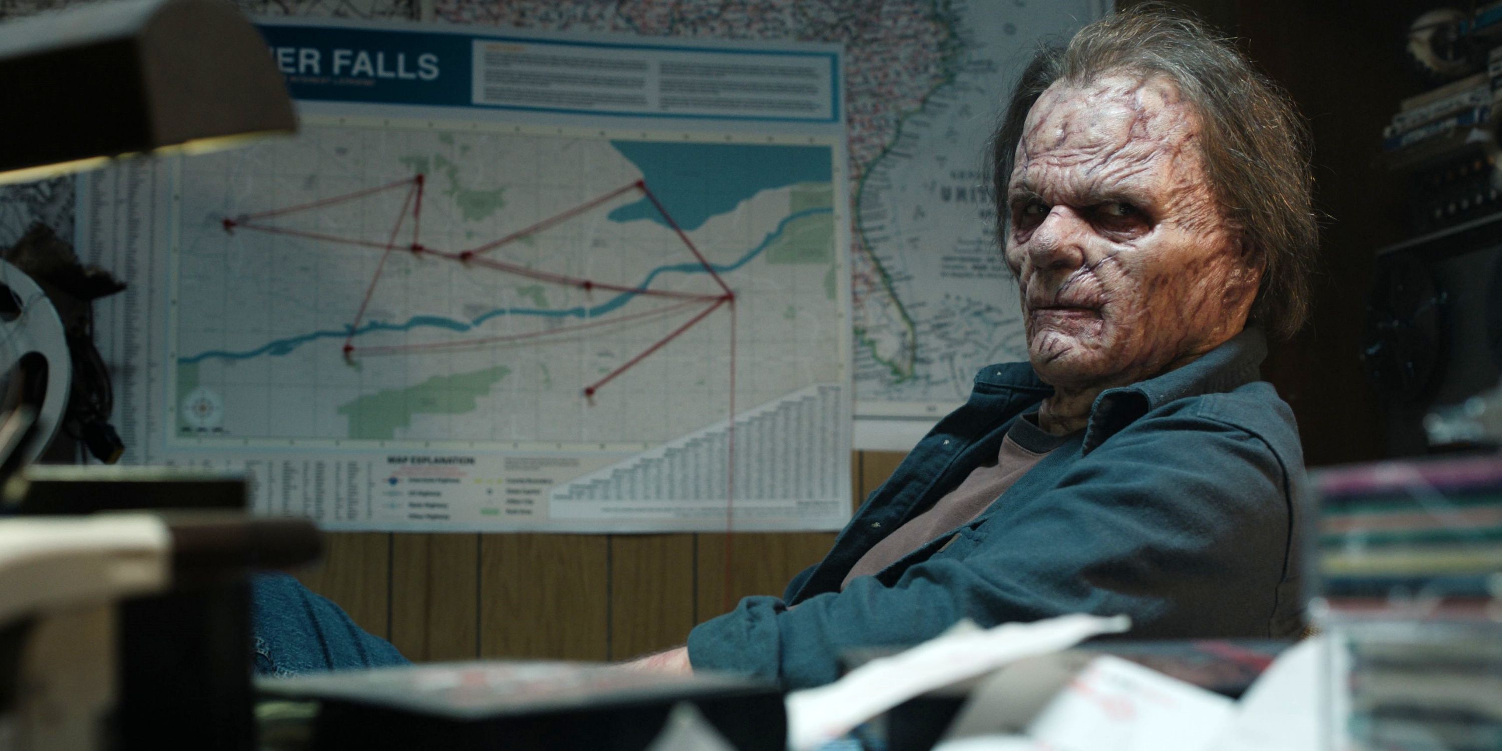 Billy Burke as Roger Bladecut sitting in a chair in full prosthetics for Bloody Axe Wound