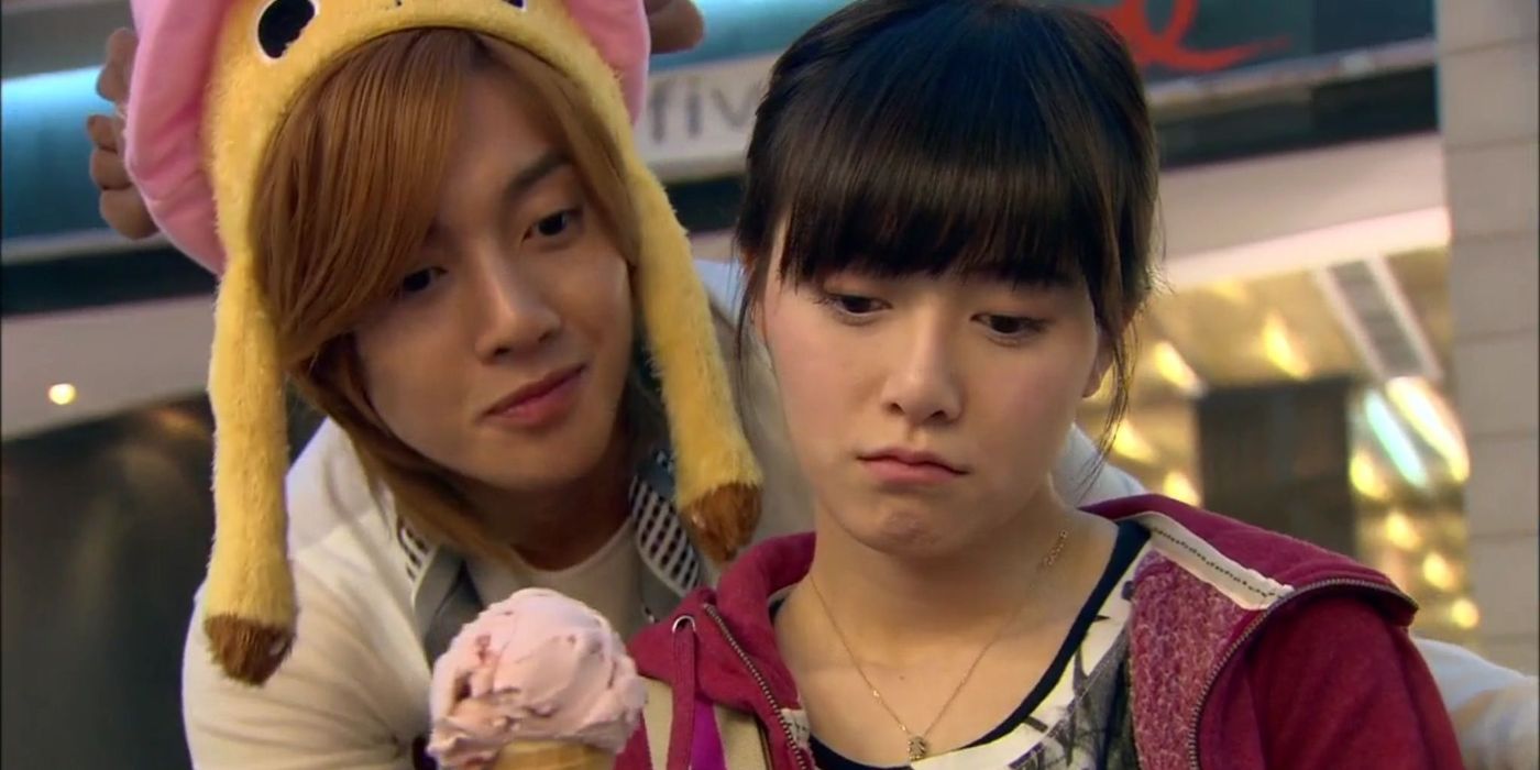 A woman looks sad as a man wearing a character hat offers her ice cream at a shopping mall in Boys Over Flowers.