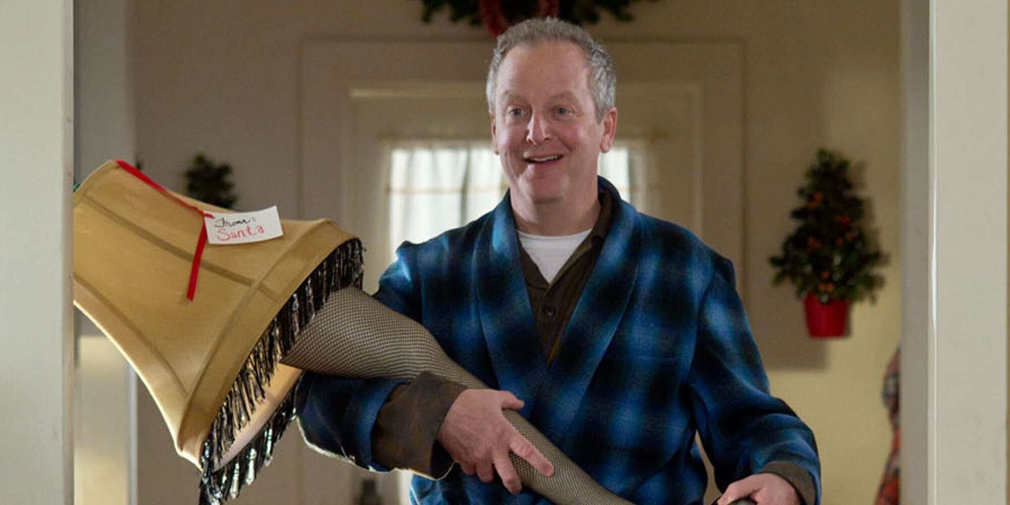 An older man holding the classic woman's leg lamp as a gift from Santa in 'A Christmas Story 2'