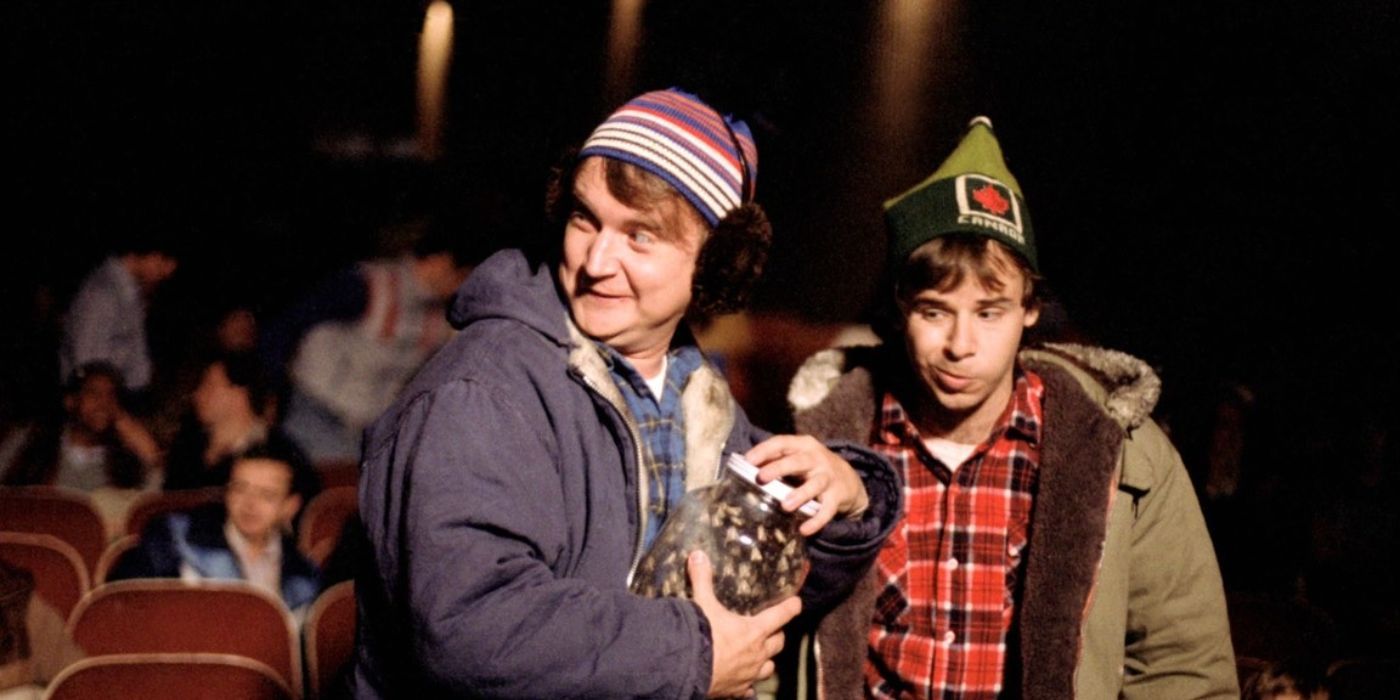 Dave Thomas as Doug and Rick Moranis as Bob sneak around a movie theater with a jar of coins in Strange Brew.