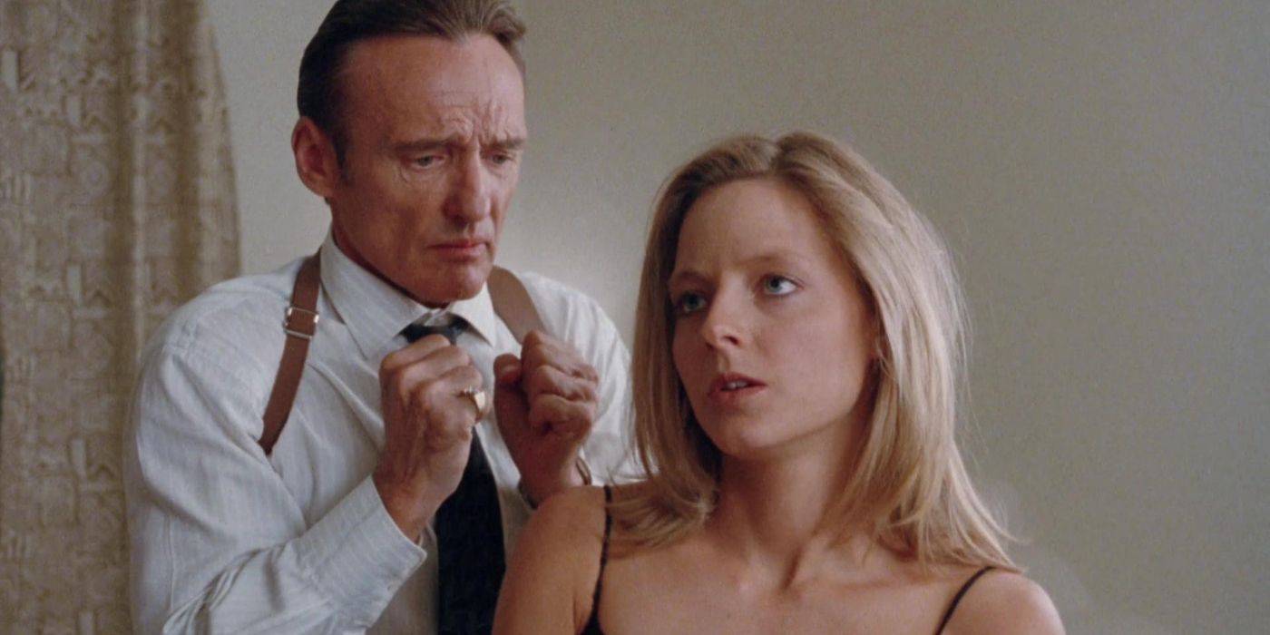A man in a shirt and tie is standing behind a woman with his fists up, while she&rsquo;s looking out and upwards, wearing a strap black top