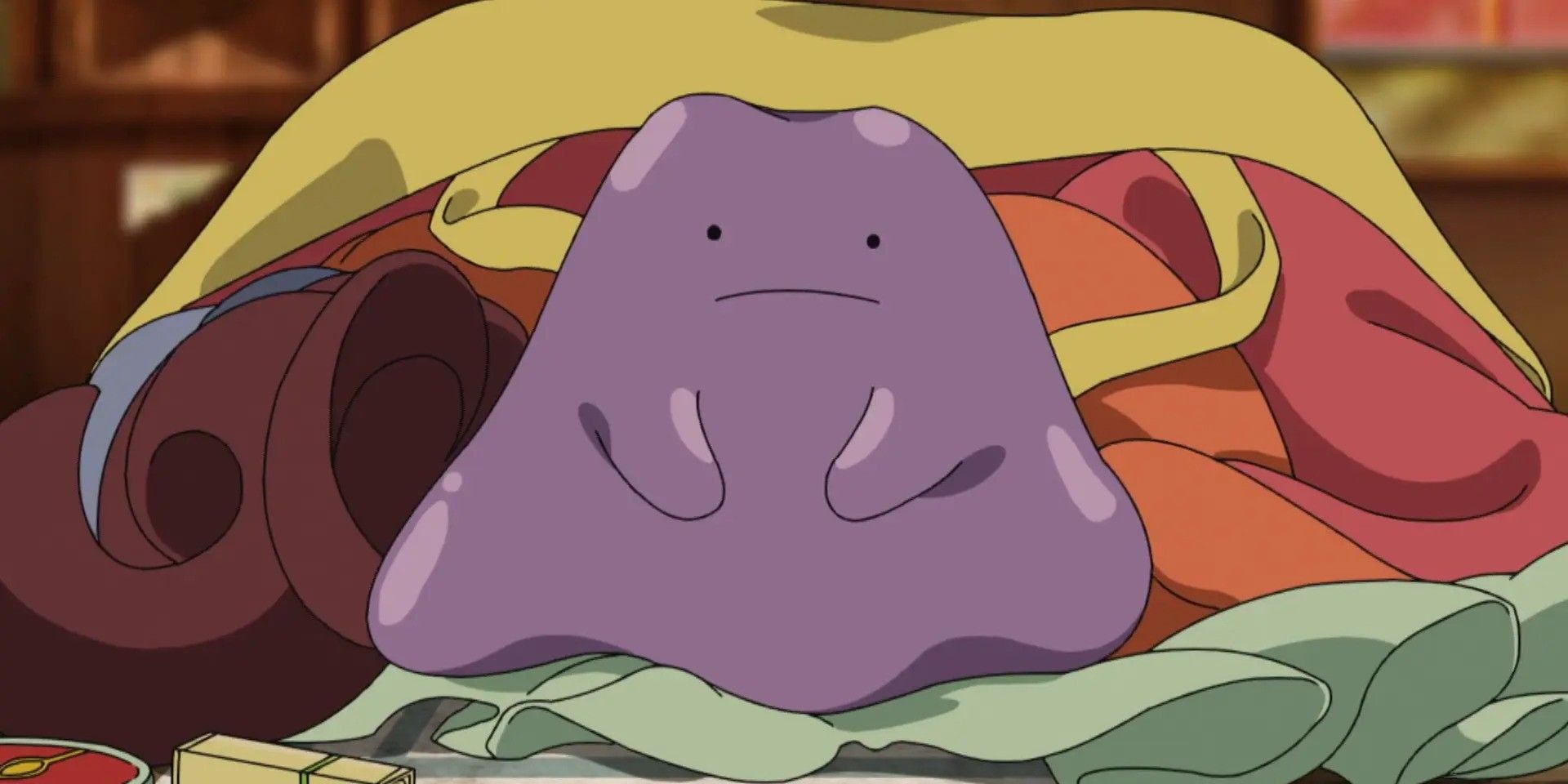 A Ditto lying on a collection of clothes with a slight frown on its face in the Pokemon Journeys anime series