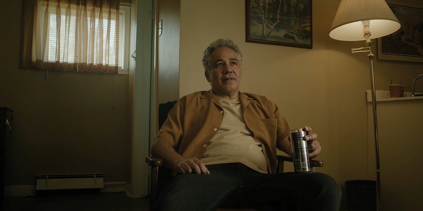 John Ortiz as Franco Quiñones sits in a chair and holds a can in a hotel room in The Madness.