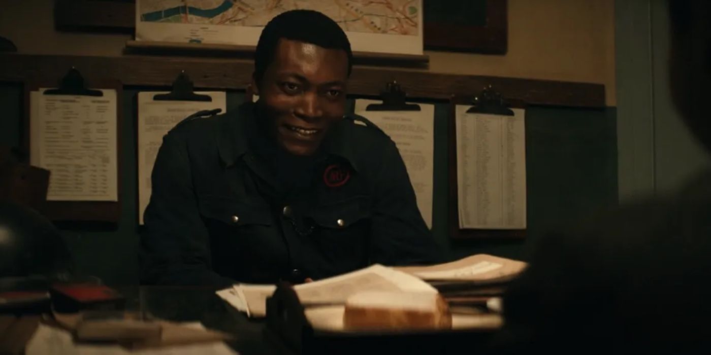 Ife (Benjamin Clementine) smiling while sitting at a desk in Steve McQueen’s Blitz