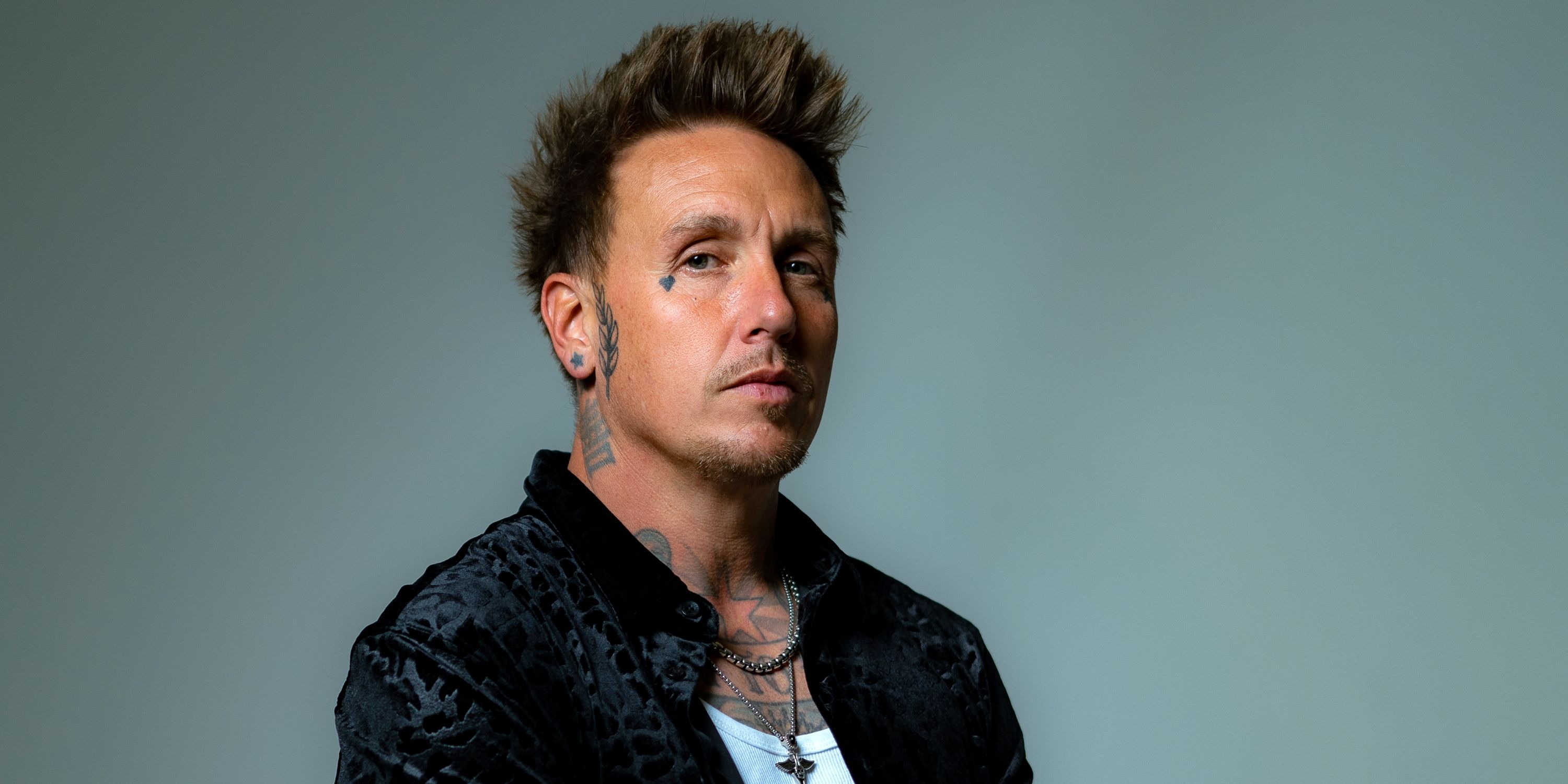 Papa Roach singer Jacoby Shaddix looking serious at the camera in a black shirt with white tank top