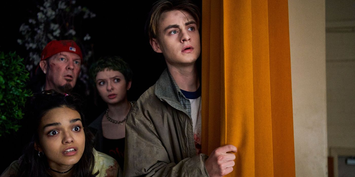 Jaeden Martell, Rachel Zegler, Fred Durst, and Lachlan Watson peeking behind a corner in Y2K.