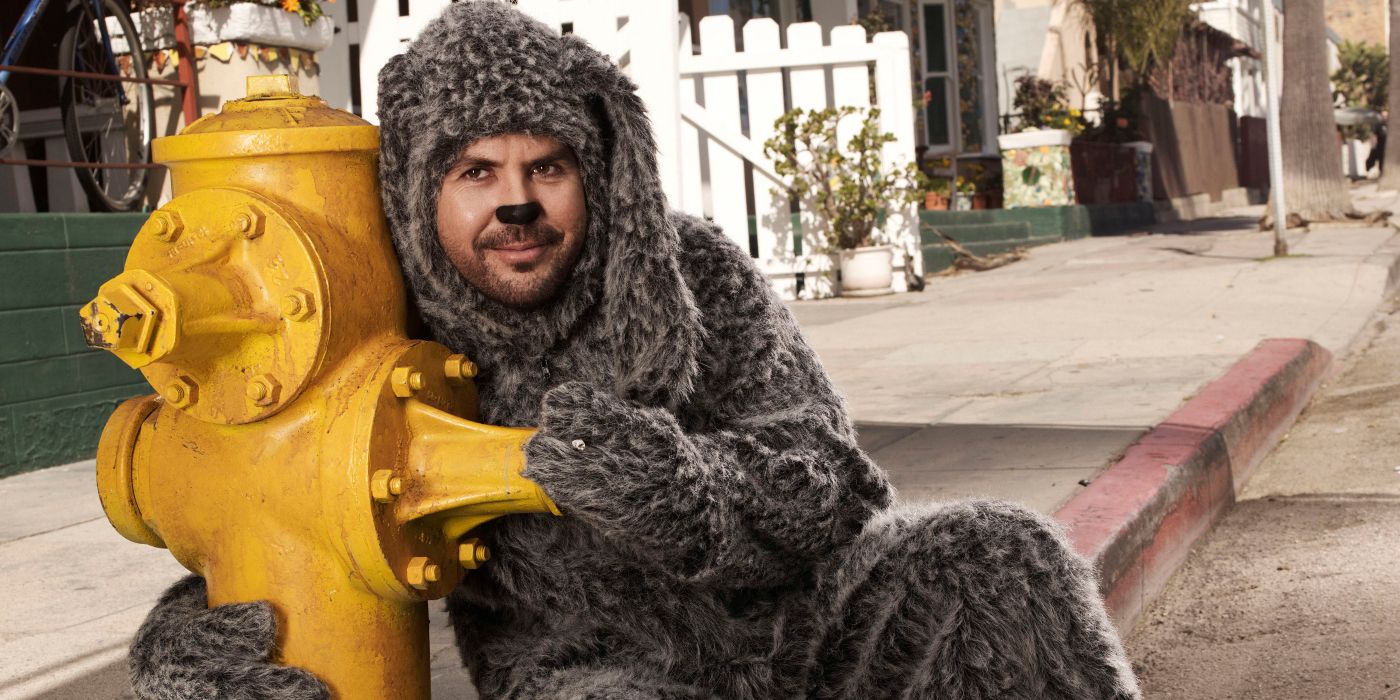 Jason Gann as Wilfred holding on to a yellow fire hydrant