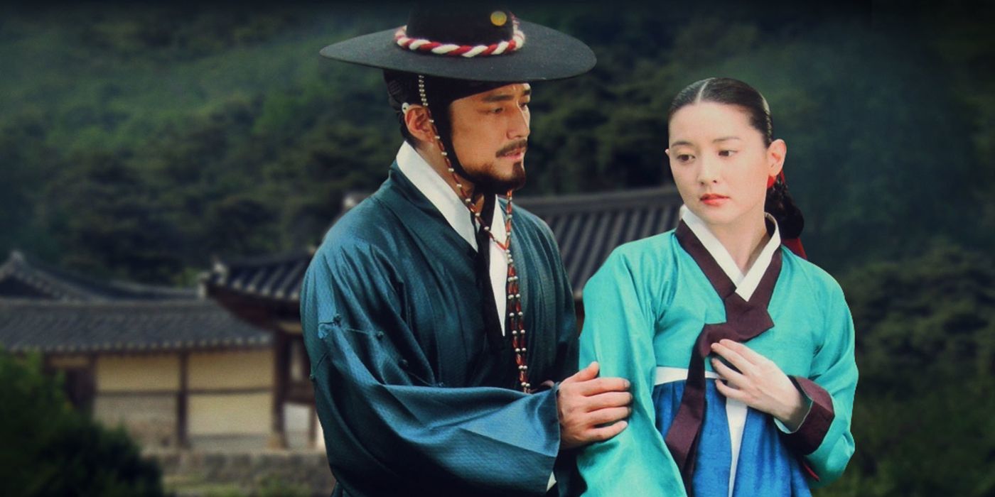 Cast from Jewel in the Palace wear traditional clothing in front of a palace surrounded by trees.