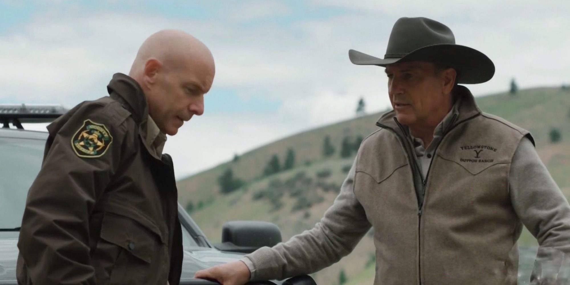 John Dutton (Kevin Costner) and Sheriff Donnie Haskell (Hugh Dillon) talk beside a squad car in 'Yellowstone's Season 2 finale.