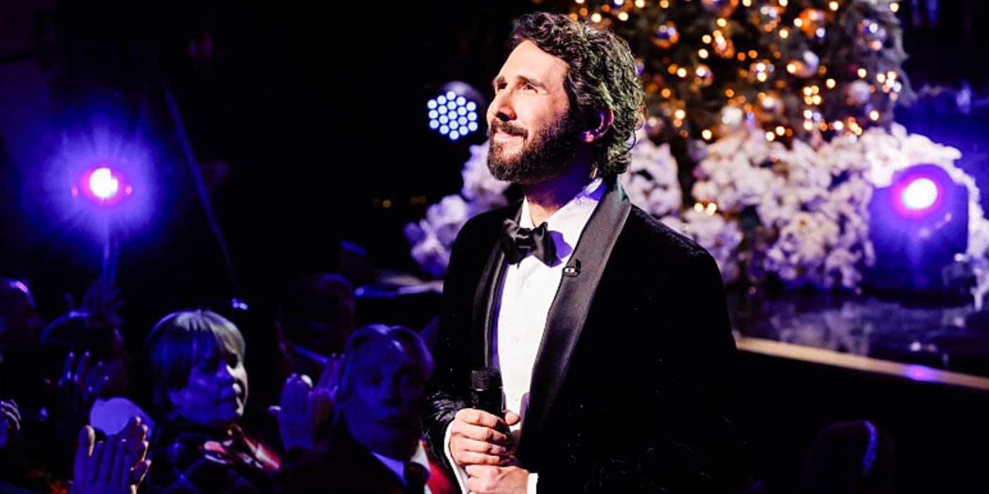 Josh Groban staring at his audience while holding a mic in Josh Groban &amp; Friends Go Home for the Holidays