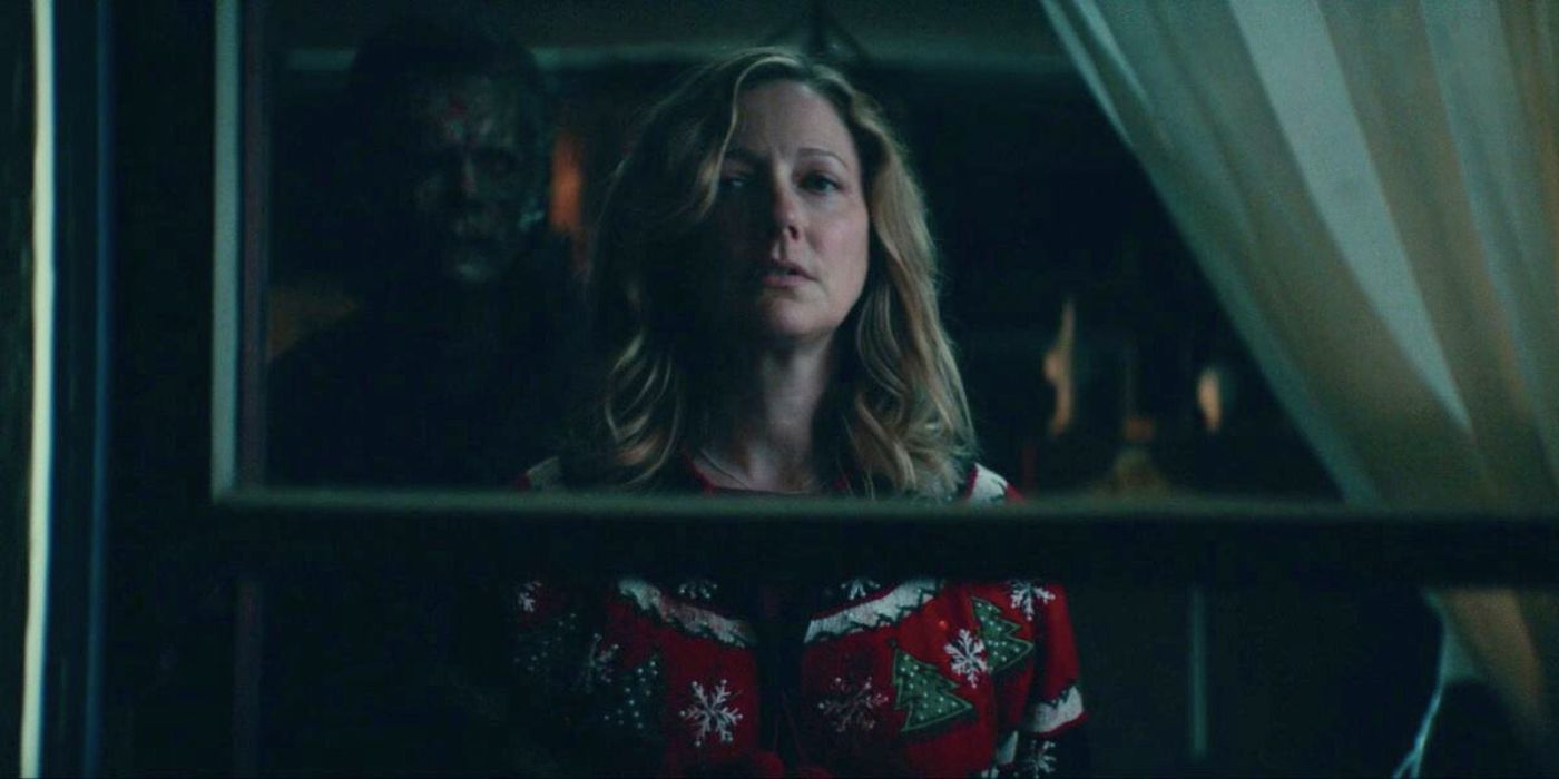 Michael Myers stands behind Karen as she looks out the window in Halloween Kills