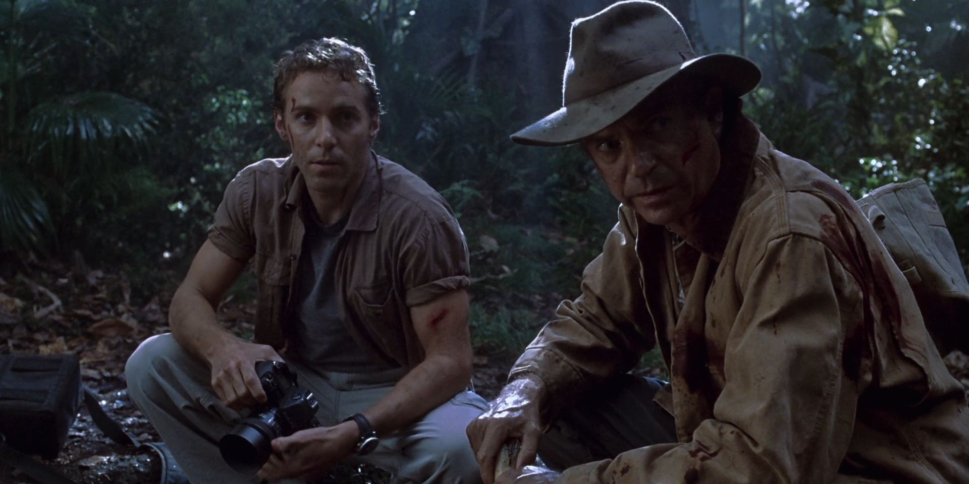 Alan Grant and Billy Brennan sit in the woods in 'Jurassic Park III'.