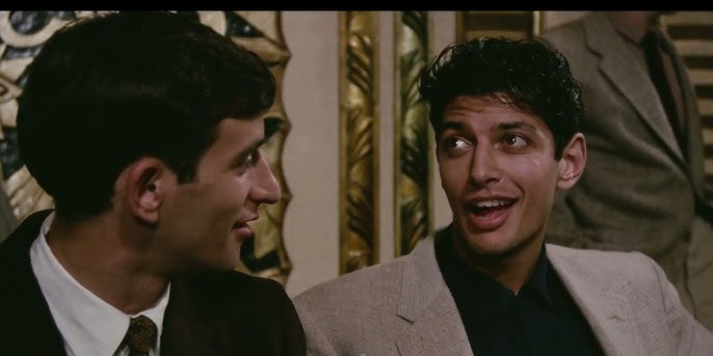 Lenny Baker and Jeff Goldblum in suits talking in a colorful room in Next Stop, Greenwich Village.