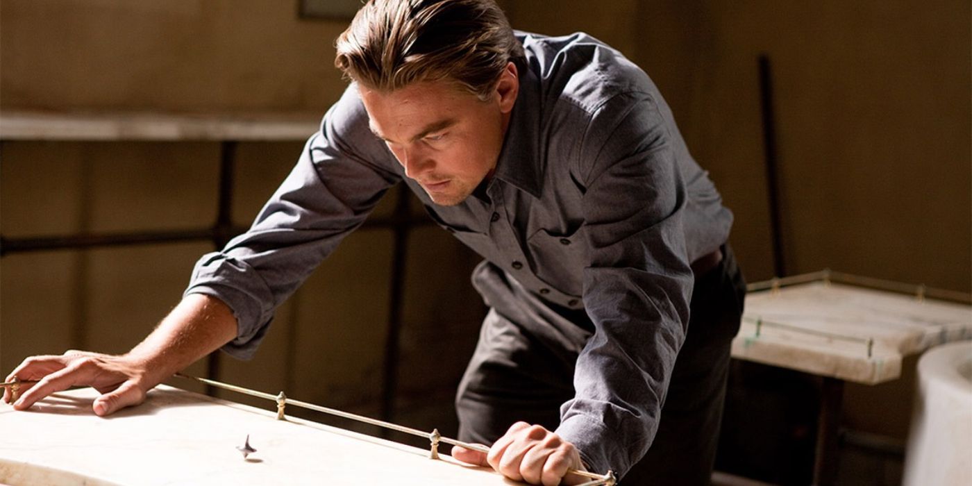 Leonardo DiCaprio intently watching a top spinning on a table in Inception.