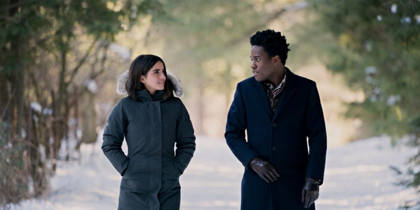 Isabela Merced and Shameik Moore walk side by side on a snowy path wearing winter coats in Let It Snow.