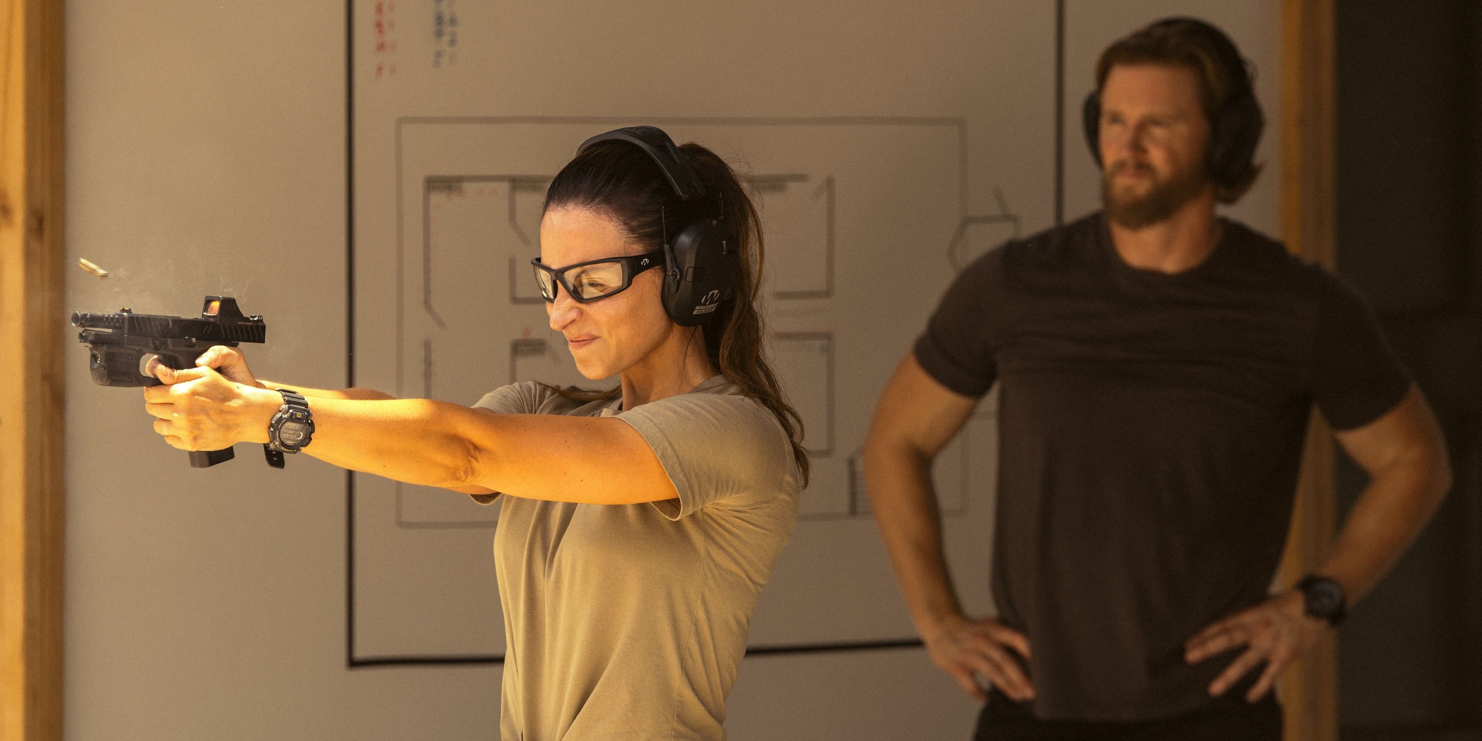 Genesis Rodriguez as Josie practicing at a gun range with Thad Luckinbill in Season 2 of Lioness