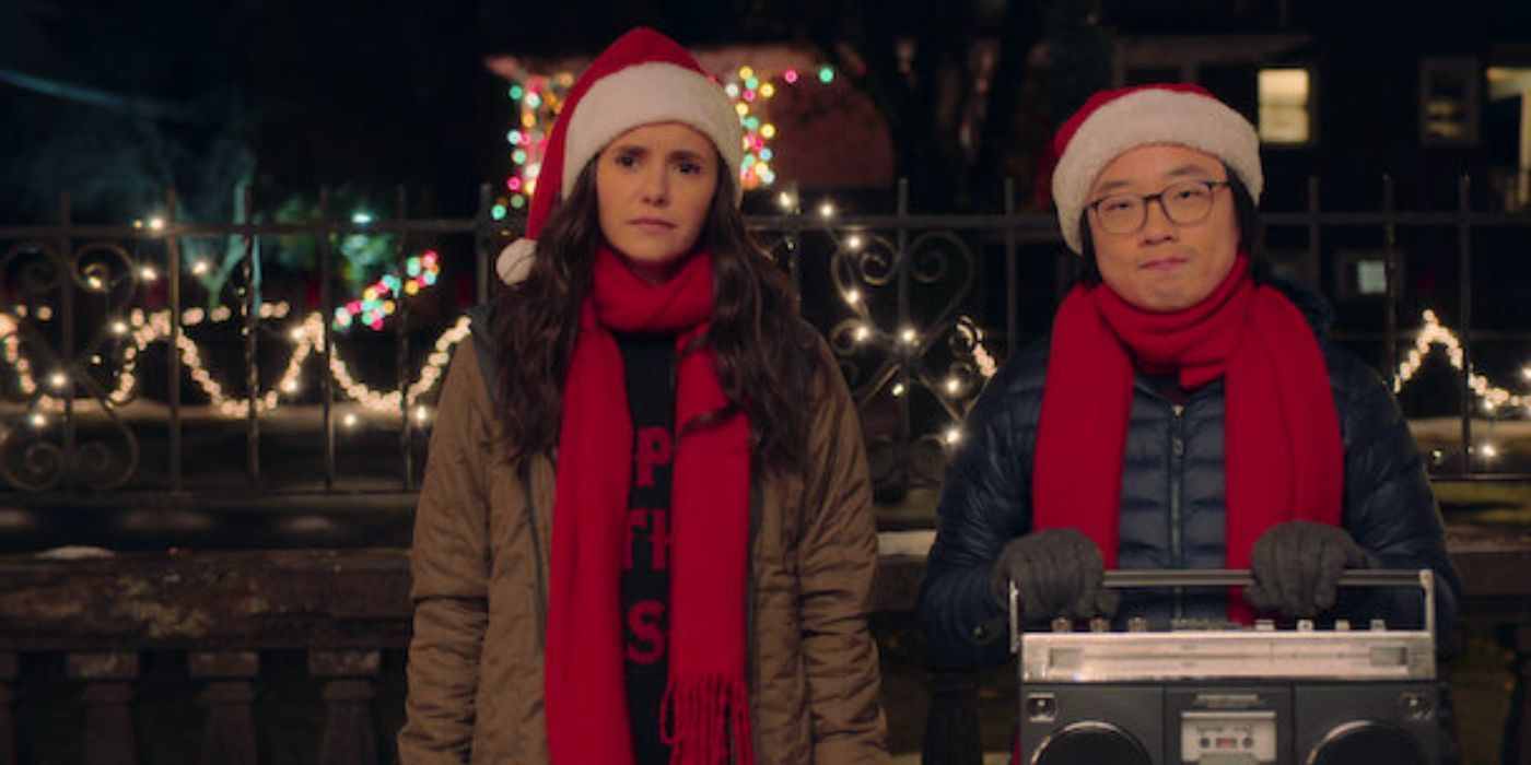 Natalie (Nina Dobrev) and Josh (Jimmy O. Yang) stand in snow as Josh holds a radio in his hands in Love Hard.