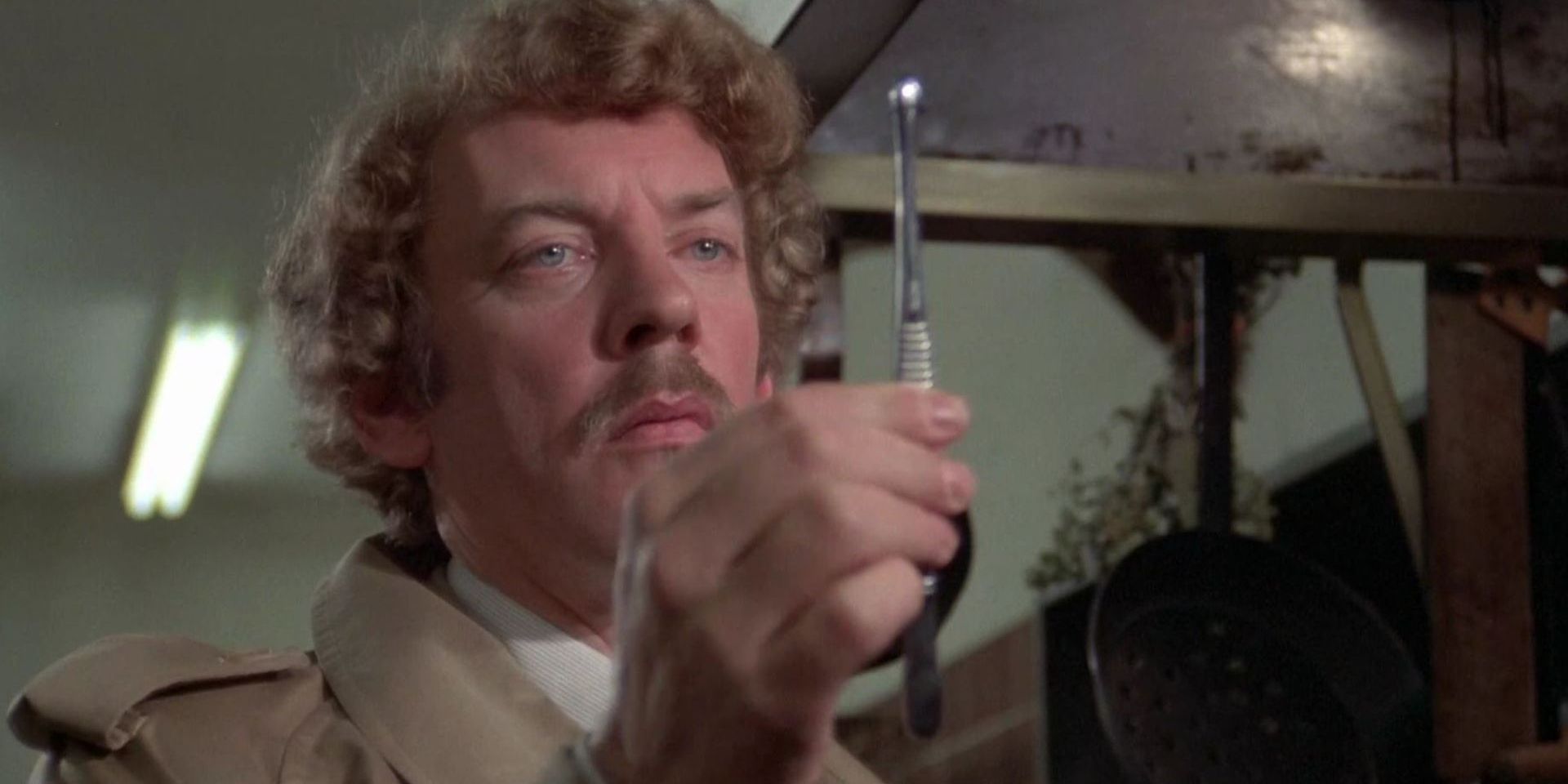 Matthew (Donald Sutherland) holding a tool in 'Invasion of the Body Snatchers'