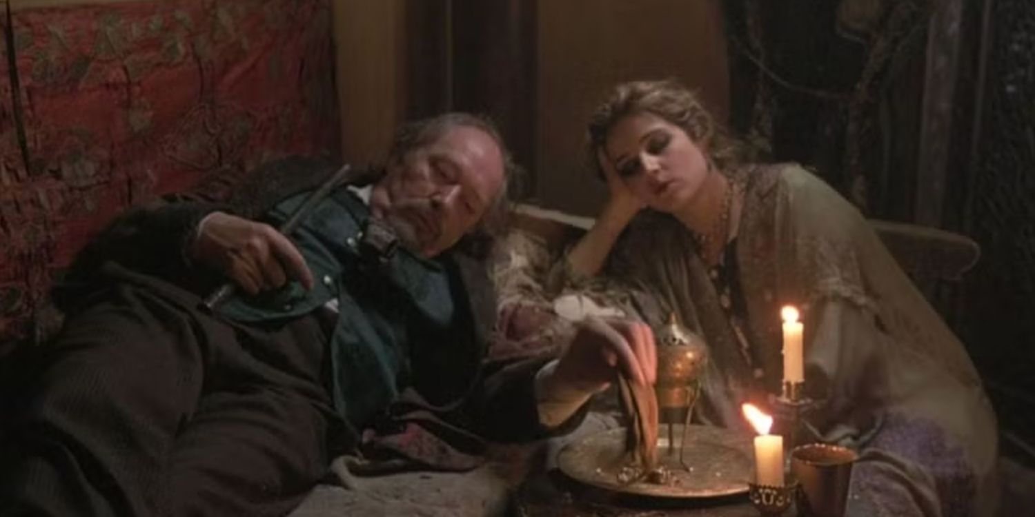 Michael Gambon as Lionel Croy reclines next to a woman in an opium den in The Wings of the Dove.