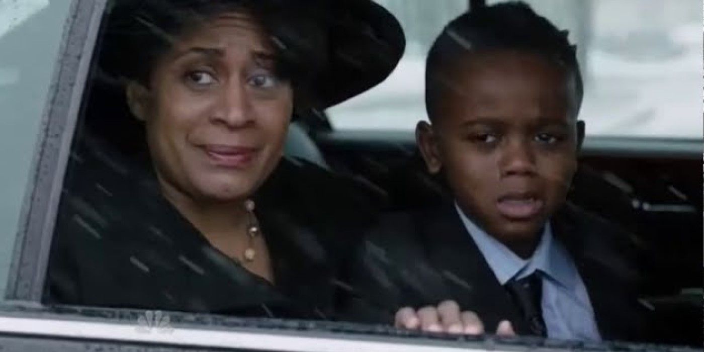 A grieving mother and brother of a dead boy looking out at Station 51 from funeral procession car in the 'Chicago Fire' episode "A Coffin That Small"