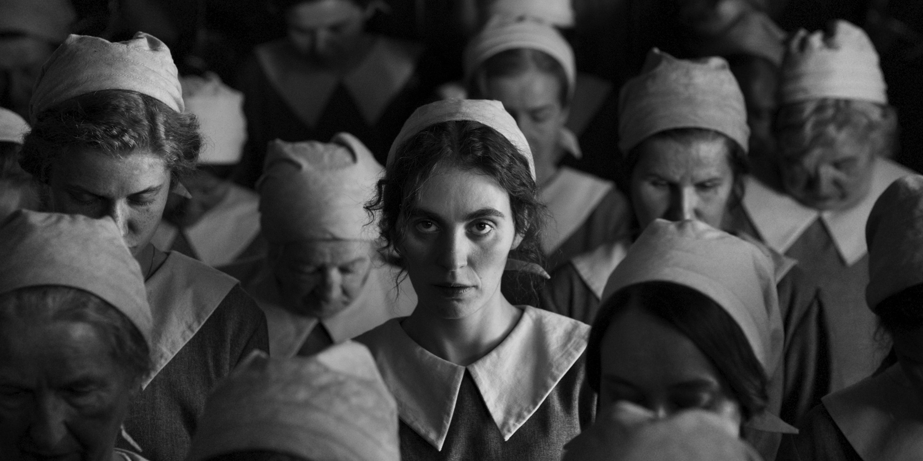 Karoline, played by actor Vic Carmen Sonne, stands among a crowd of factory workers in The Girl With The Needle