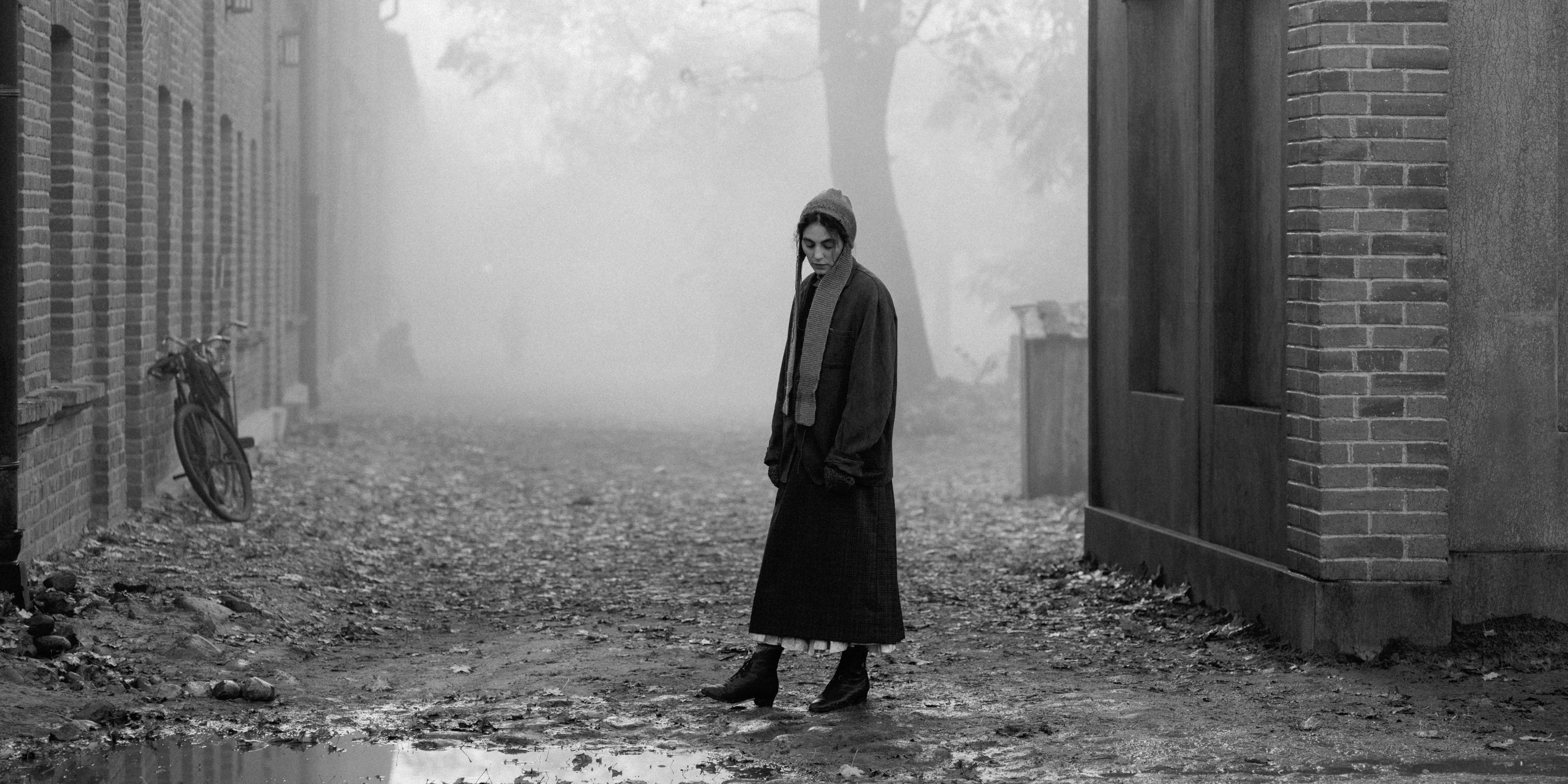 Karoline, played by actor Vic Carmen Sonne, stands in a derelict street in The Girl With The Needle.
