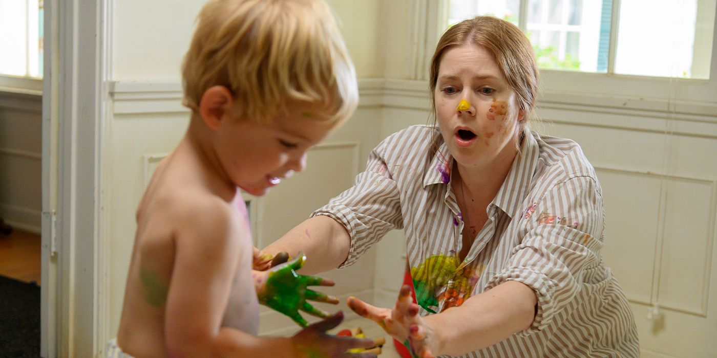 Mother (Amy Adams) covered in paint reaching out to her child with paint all over his hands in Nightbitch