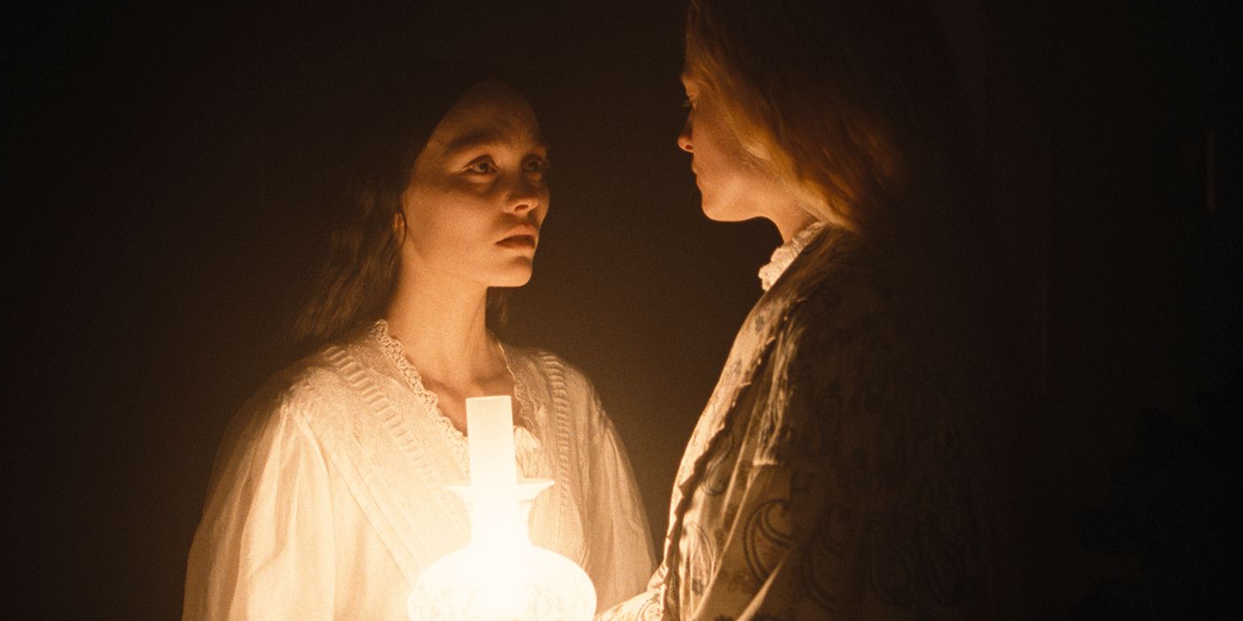 Ellen (Lily-Rose Depp) and Anna (Emma Corrin) in the dark with an oil lamp in Nosferatu